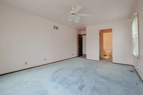 an empty room with chandelier fan and windows