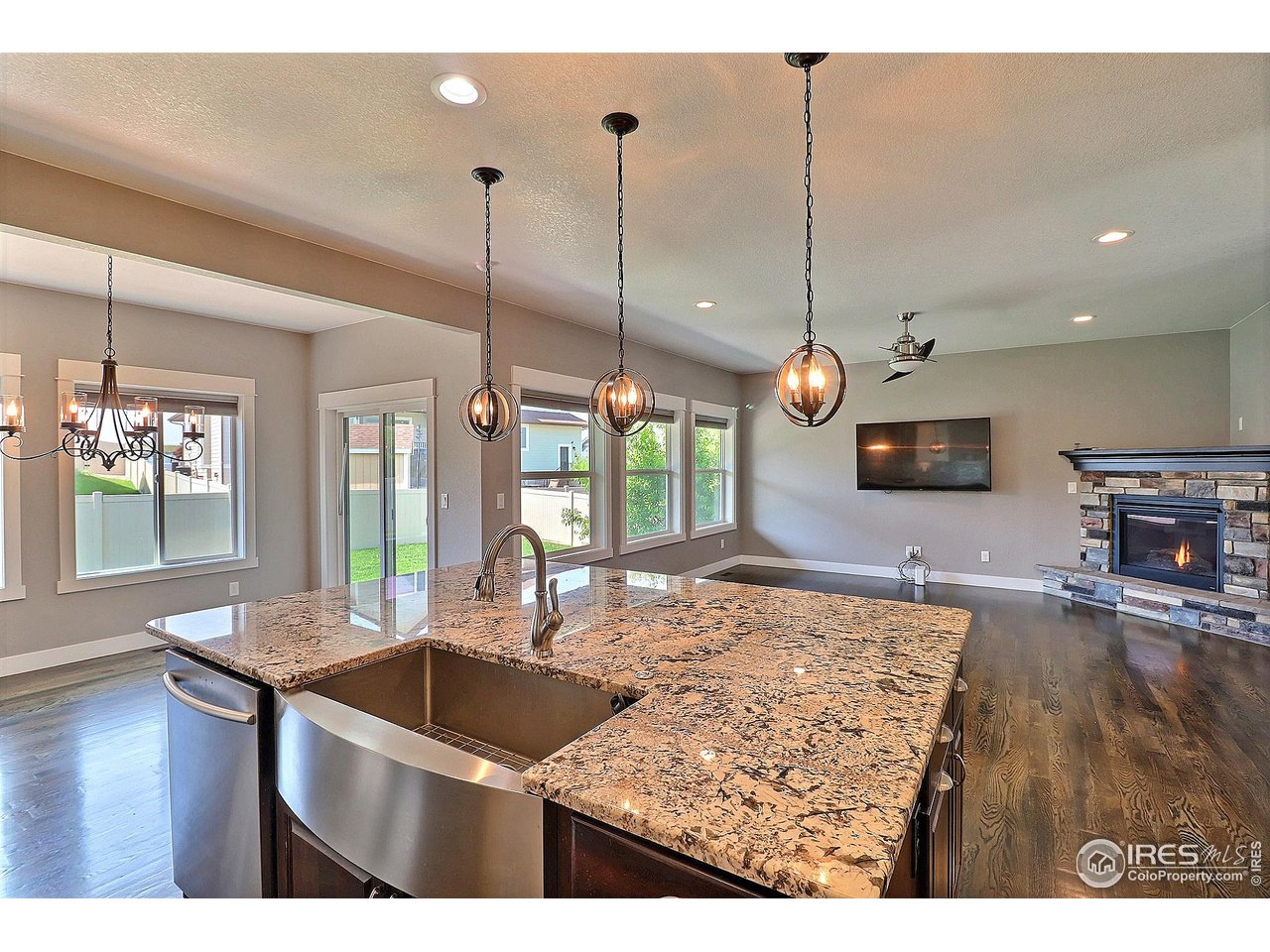 9004 19th Street Greeley, CO 80634 - Photo 16 of 49 a kitchen with kitchen island granite countertop a sink a counter top space and living room view