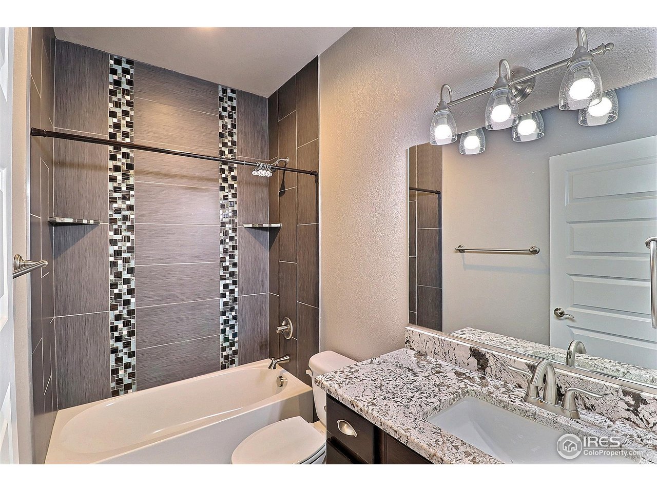 9004 19th Street Greeley, CO 80634 - Photo 36 of 49 a bathroom with a granite countertop sink a toilet and shower
