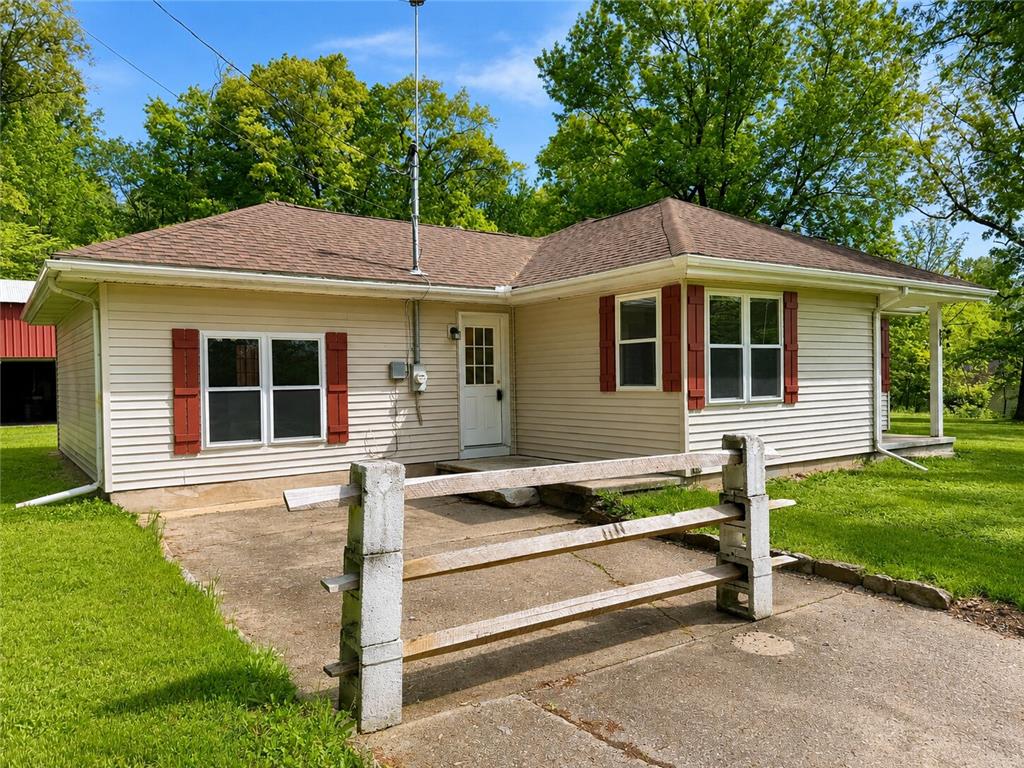 4995 Mountain Road Slatington, PA 18080 - Photo 2 of 30 A cream-colored home with vibrant red shutters and a welcoming front door, nestled amidst a lush green lawn.