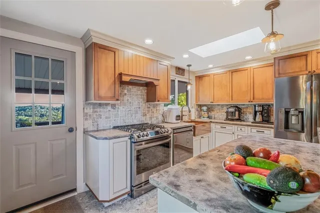 a kitchen with stainless steel appliances granite countertop a stove top oven a sink dishwasher and cabinets with wooden floor