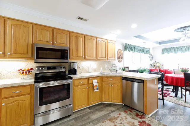 a kitchen with stainless steel appliances a stove a sink cabinets and a microwave