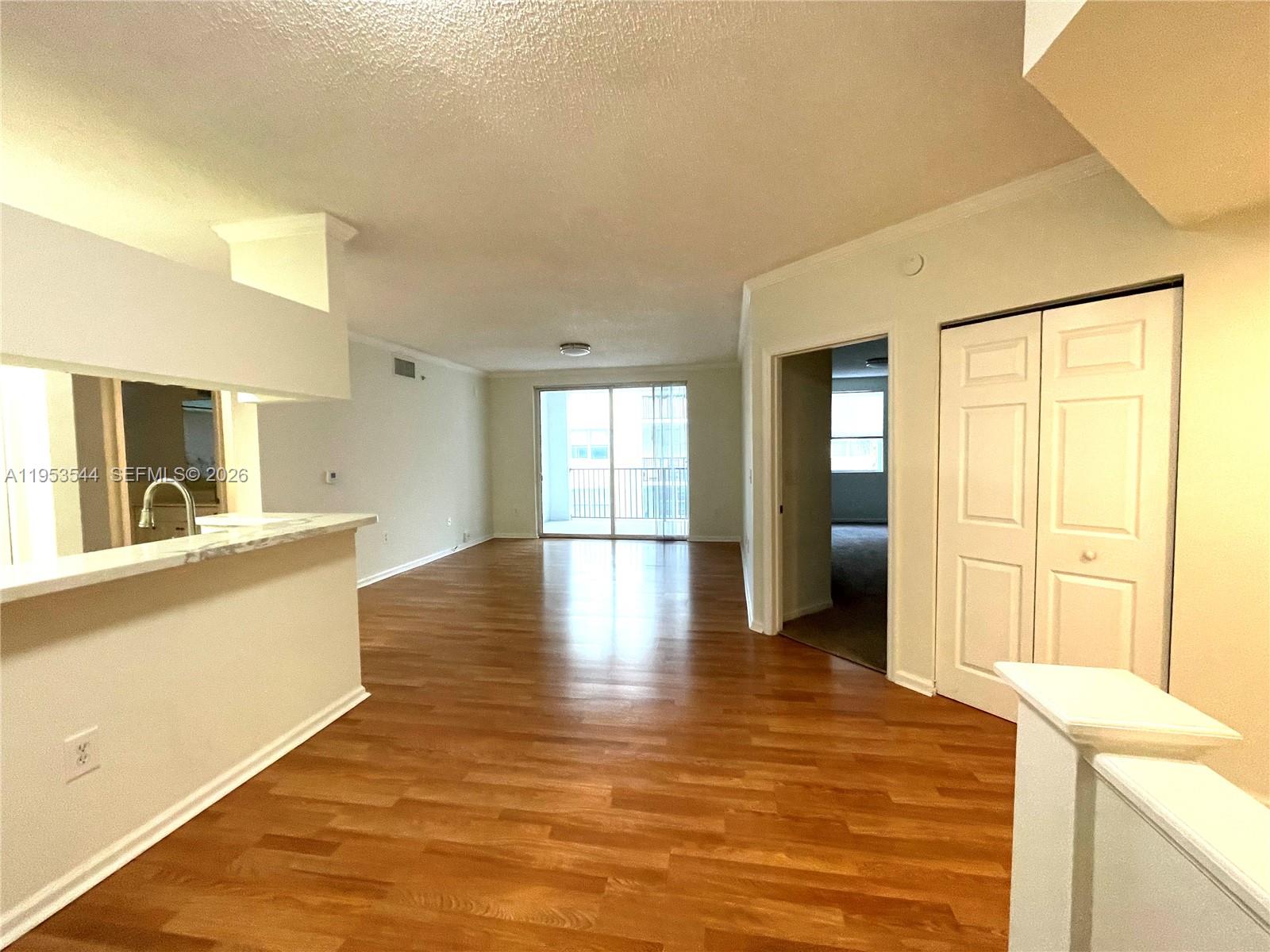 17125 North Bay Road, Unit 3404 Sunny Isles Beach, FL 33160 - Photo 11 of 20 a view of a kitchen with kitchen island a sink wooden floor and a large window