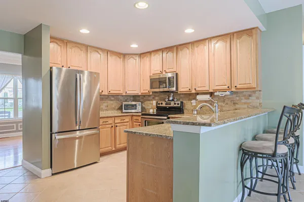 a kitchen with stainless steel appliances granite countertop a refrigerator a stove a sink and a microwave