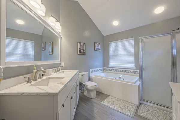 a bathroom with a granite countertop sink a toilet a large mirror a bathtub and window