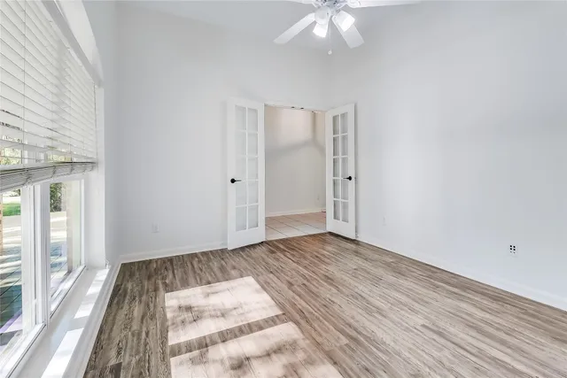 a view of an empty room with wooden floor and a window