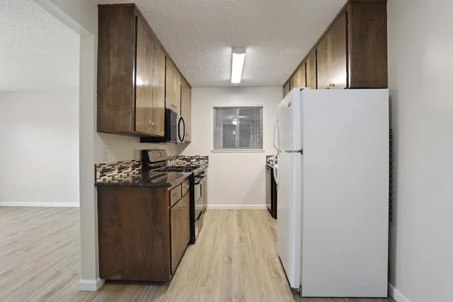 a kitchen with stainless steel appliances granite countertop a refrigerator and a stove
