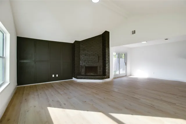 a view of an empty room with wooden floor and a fireplace