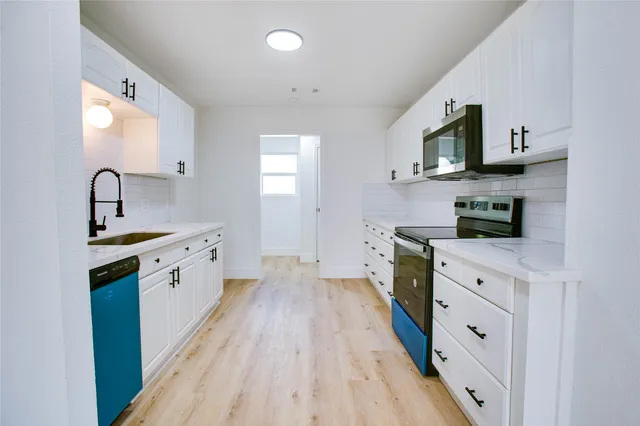 a kitchen with white cabinets stainless steel appliances and sink