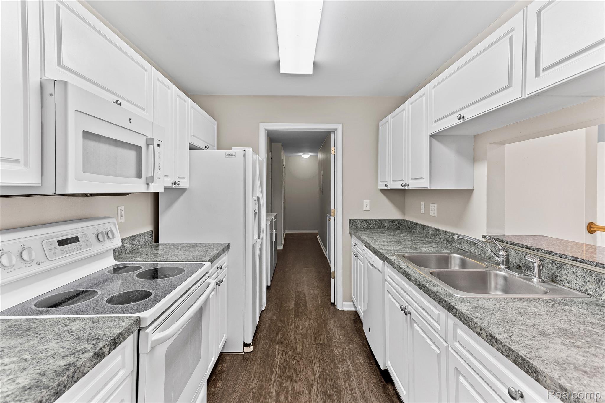 3553 Oakmonte Boulevard Rochester, MI 48306 - Photo 3 of 42 Galley kitchen featuring white cabinetry, gray speckled countertops, a built-in microwave, an electric range, and wood-finish flooring