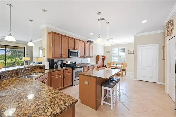 a kitchen with stainless steel appliances granite countertop a sink a stove a refrigerator cabinets and living room view