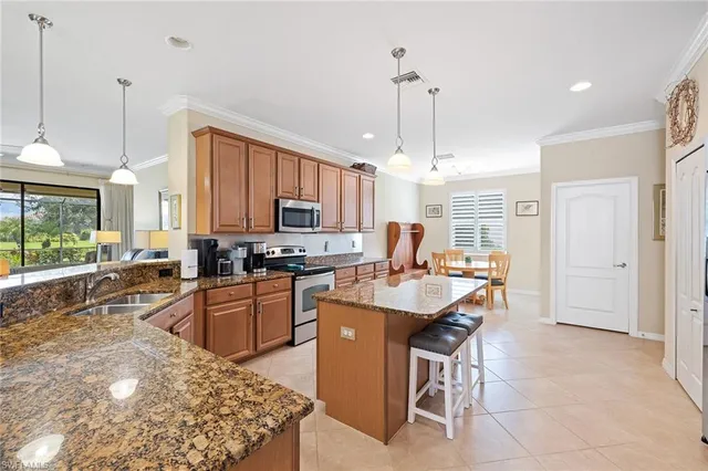 a kitchen with stainless steel appliances granite countertop a sink a stove a refrigerator cabinets and living room view