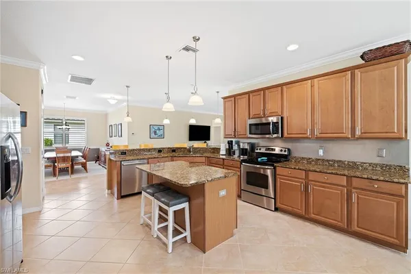 a open kitchen with stainless steel appliances granite countertop a stove top oven a sink dishwasher a dining table and chairs with wooden floor