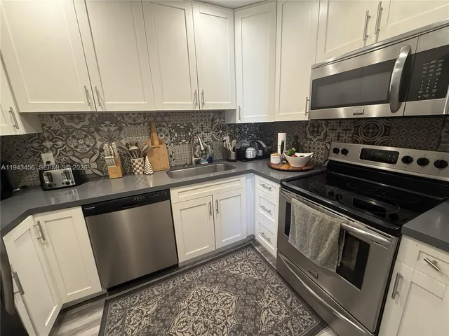 a kitchen with stainless steel appliances granite countertop a sink stove and microwave