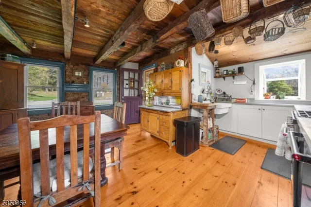 a dining hall with stainless steel appliances kitchen island granite countertop a table chairs in it and wooden floors