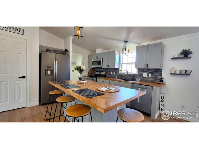 a kitchen with stainless steel appliances granite countertop a sink a stove a refrigerator a dining table and chairs