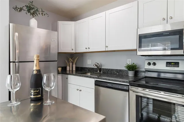 a kitchen with stainless steel appliances granite countertop a sink a stove and a refrigerator