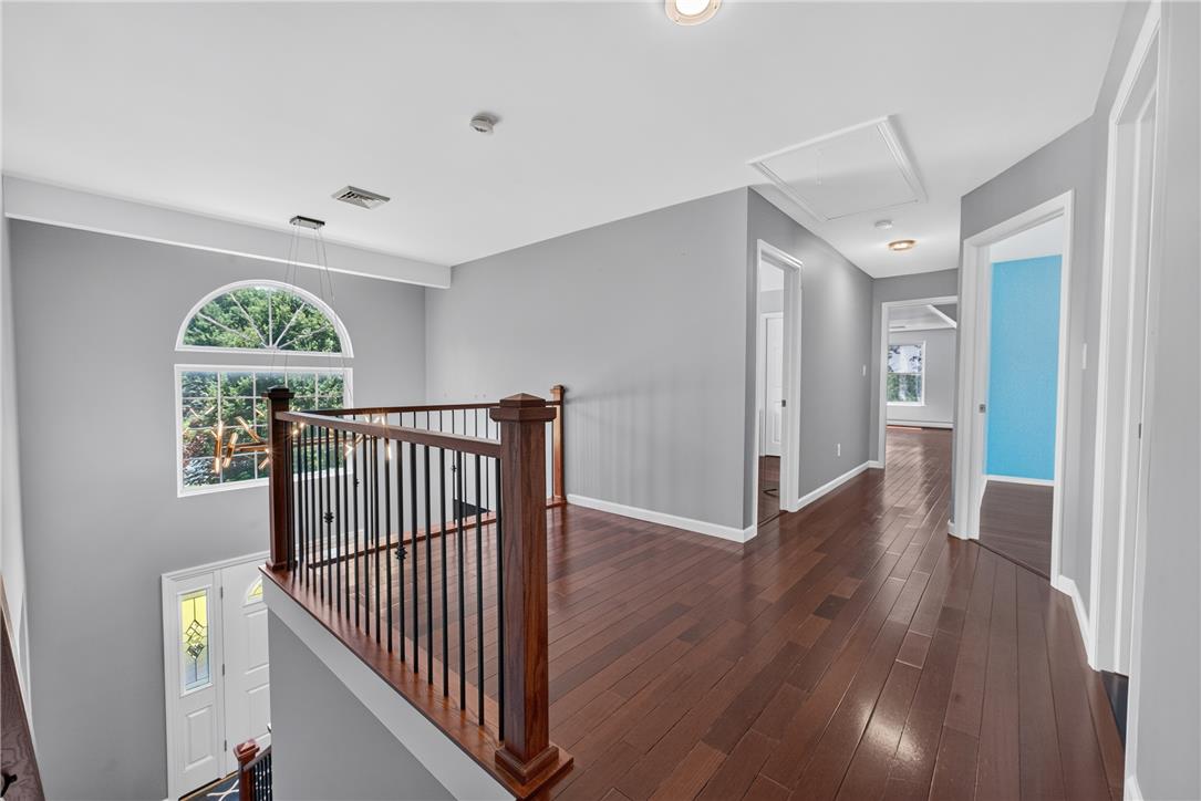220 Pennbrook Road Stroudsburg, PA 18360 - Photo 24 of 60 A graceful staircase with a polished wood banister leads to a sun-drenched upper-level hallway with rich hardwood flooring.
