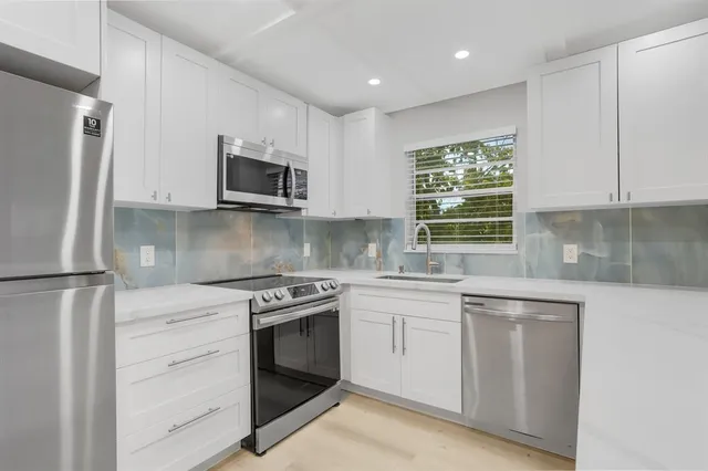 a kitchen with white cabinets stainless steel appliances and a window