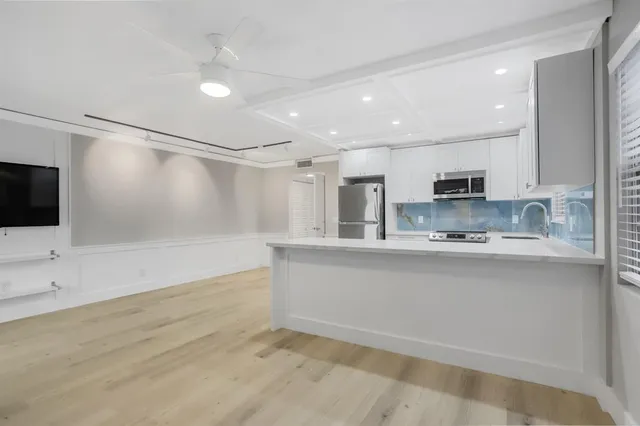 a large white kitchen with stainless steel appliances granite countertop a stove a sink and a refrigerator