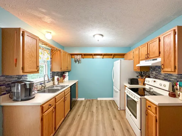 a kitchen with stainless steel appliances granite countertop a refrigerator a sink and dishwasher with wooden floor