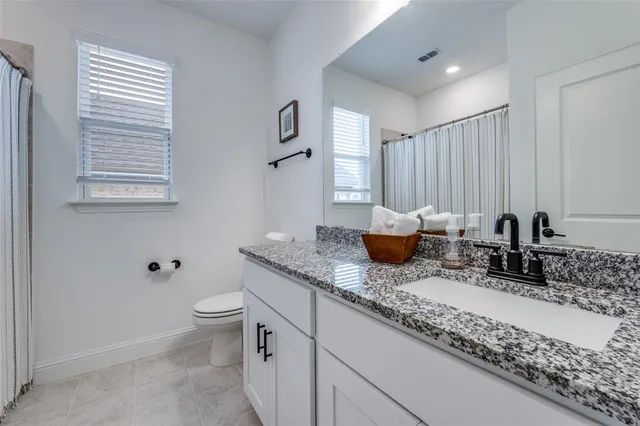 a bathroom with a granite countertop sink a toilet and a mirror