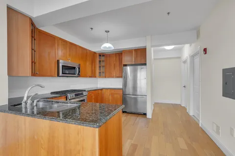 a kitchen with stainless steel appliances granite countertop a refrigerator a sink a stove with wooden cabinets