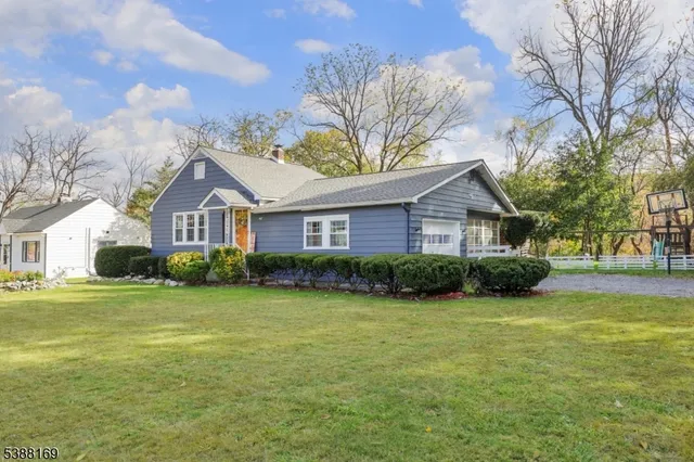 a front view of a house with garden and trees