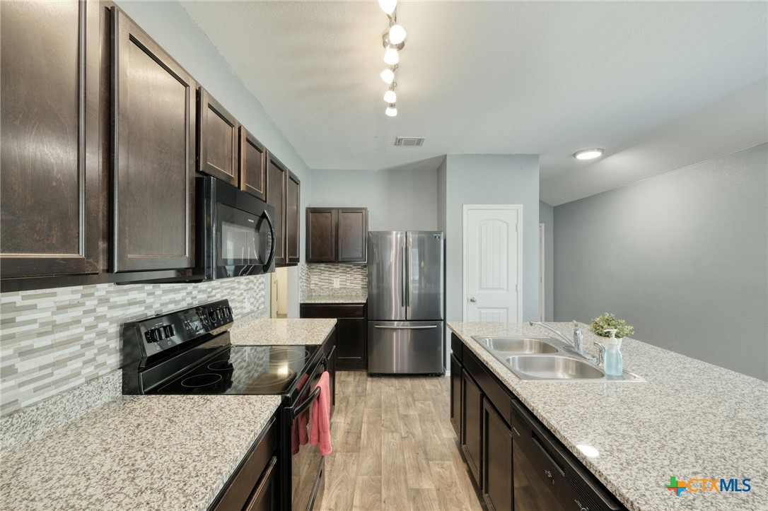 14905 Breccia Road Manor, TX 78653 - Photo 4 of 13 Dark colored cabinets throughout allow plenty of space for organization.