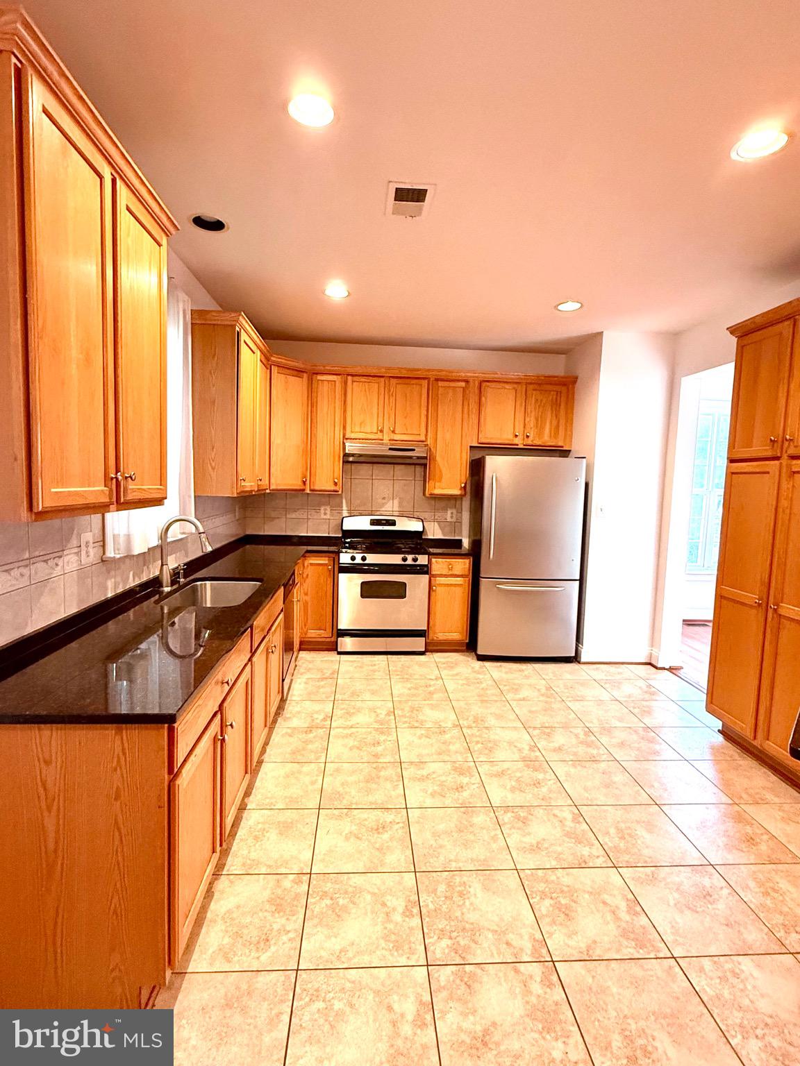12447 Red Patch Lane Fairfax, VA 22033 - Photo 7 of 34 a large kitchen with stainless steel appliances kitchen island granite countertop a refrigerator a stove top oven and a sink