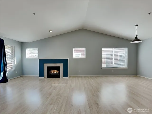 an empty room with windows and fireplace