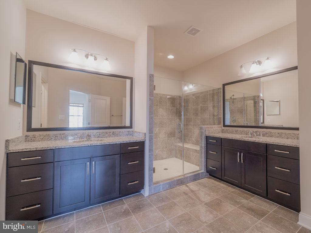 22595 Windsor Locks Square Ashburn, VA 20148 - Photo 39 of 56 a spacious bathroom with a granite countertop sink a mirror a bathtub and a shower
