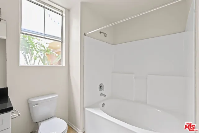 a white toilet sitting next to a bath tub