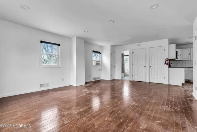 a view of an empty room with window and wooden floor