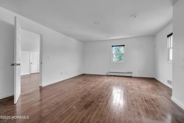 an empty room with wooden floor and window