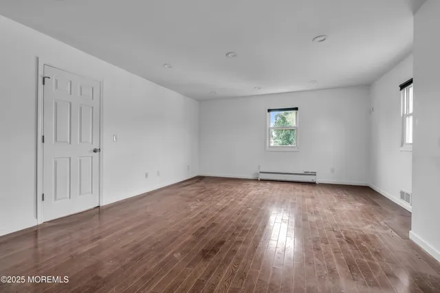 an empty room with wooden floor and window