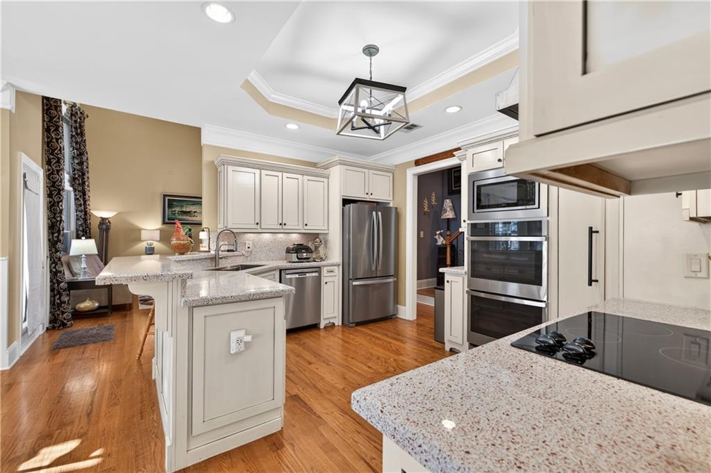 905 Old Forge Lane Jefferson, GA 30549 - Photo 16 of 69 a kitchen with stainless steel appliances kitchen island granite countertop a refrigerator oven a sink dishwasher and white cabinets with wooden floor