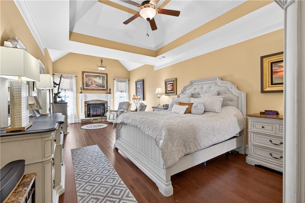 905 Old Forge Lane Jefferson, GA 30549 - Photo 30 of 69 a spacious bedroom with a large bed a fireplace and a chandelier