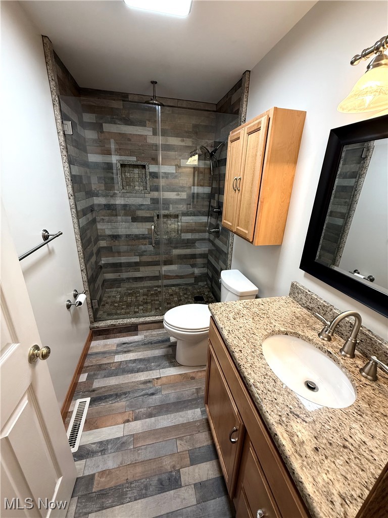 5115 Raspberry Lane Mineral Ridge, OH 44440 - Photo 19 of 25 Bathroom with visible vents, toilet, a stall shower, wood finished floors, and vanity