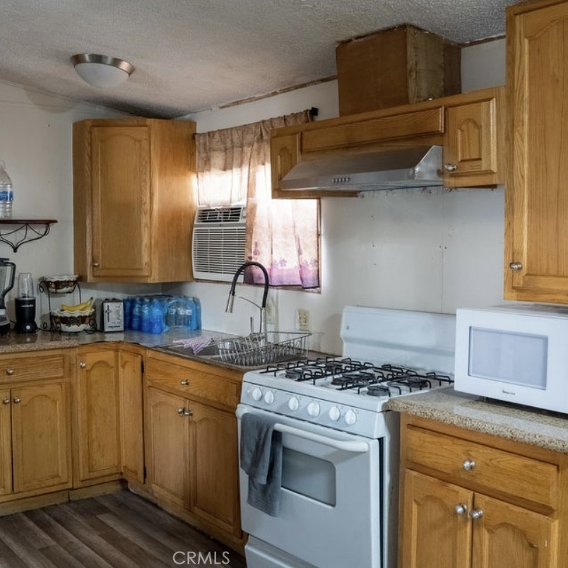 7717 Church Avenue, Unit 54 Highland, CA 92346 - Photo 4 of 13 a kitchen with stainless steel appliances granite countertop a sink a stove and a wooden cabinets