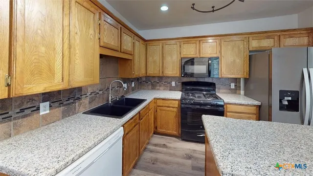 a kitchen with stainless steel appliances granite countertop a stove a sink and a microwave