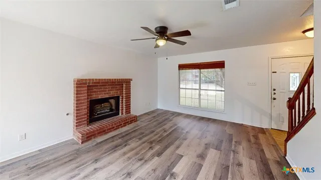 a view of empty room with wooden floor fireplace and a window