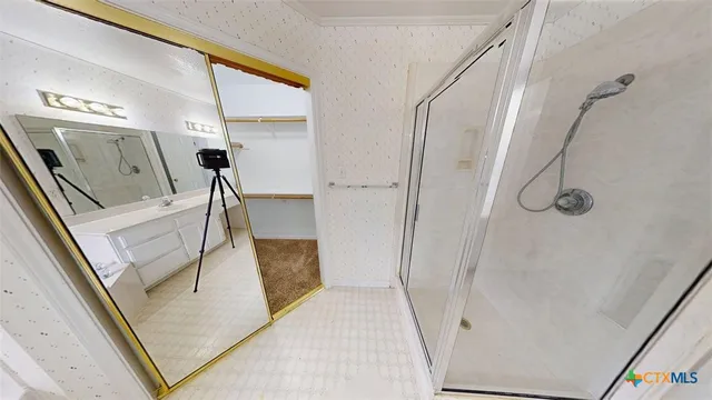 a bathroom with a glass door shower and vanity