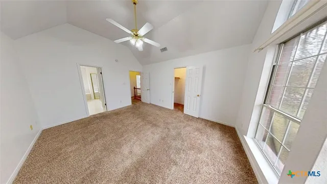 a view of a big room with windows and chandelier fan