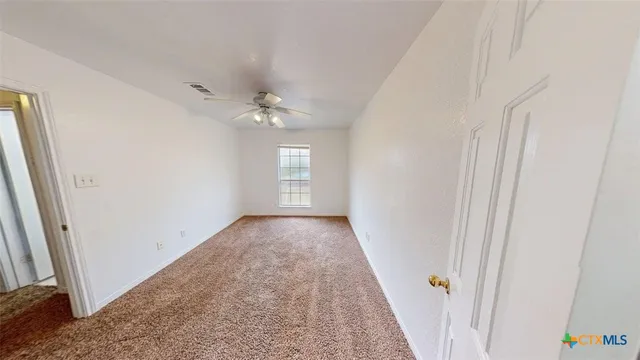 a view of empty room with a ceiling fan and window