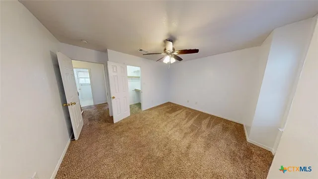 an empty room with a chandelier fan and windows