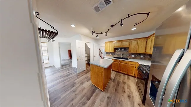 a kitchen with stainless steel appliances refrigerator wooden floor dining table and chair