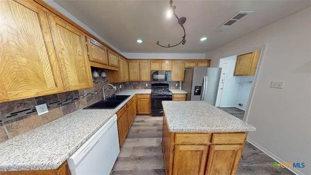 a large kitchen with kitchen island a large counter top space a sink stainless steel appliances and cabinets