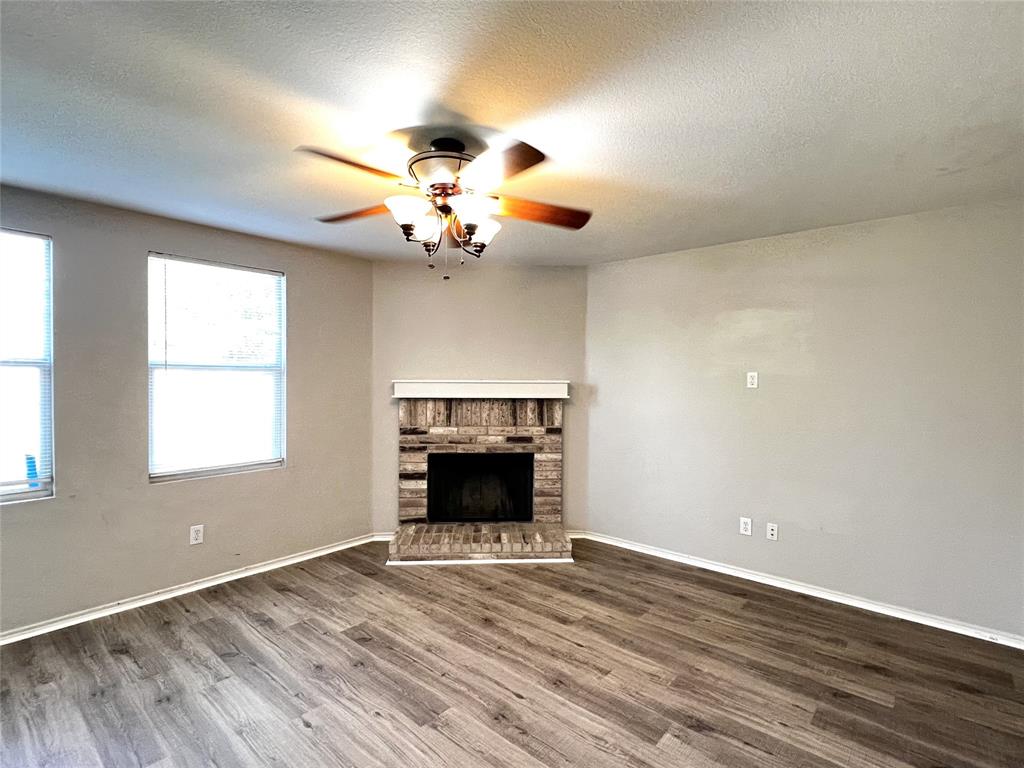 12864 Cowper Drive Frisco, TX 75035 - Photo 11 of 28 an empty room with wooden floor fireplace and windows
