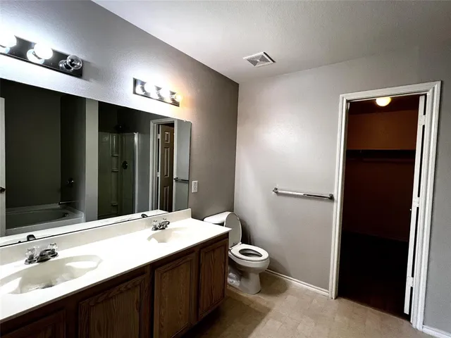 a bathroom with a double vanity sink toilet and mirror